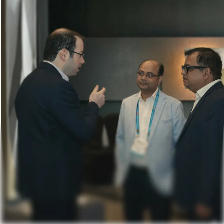 Three men in business attire engaged in conversation in a formal indoor setting