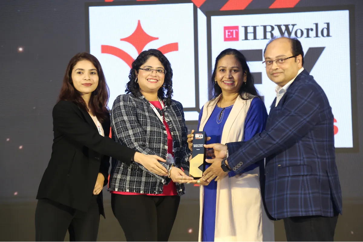 Four professionals holding an award on stage with ET HRWorld EX Awards backdrop.