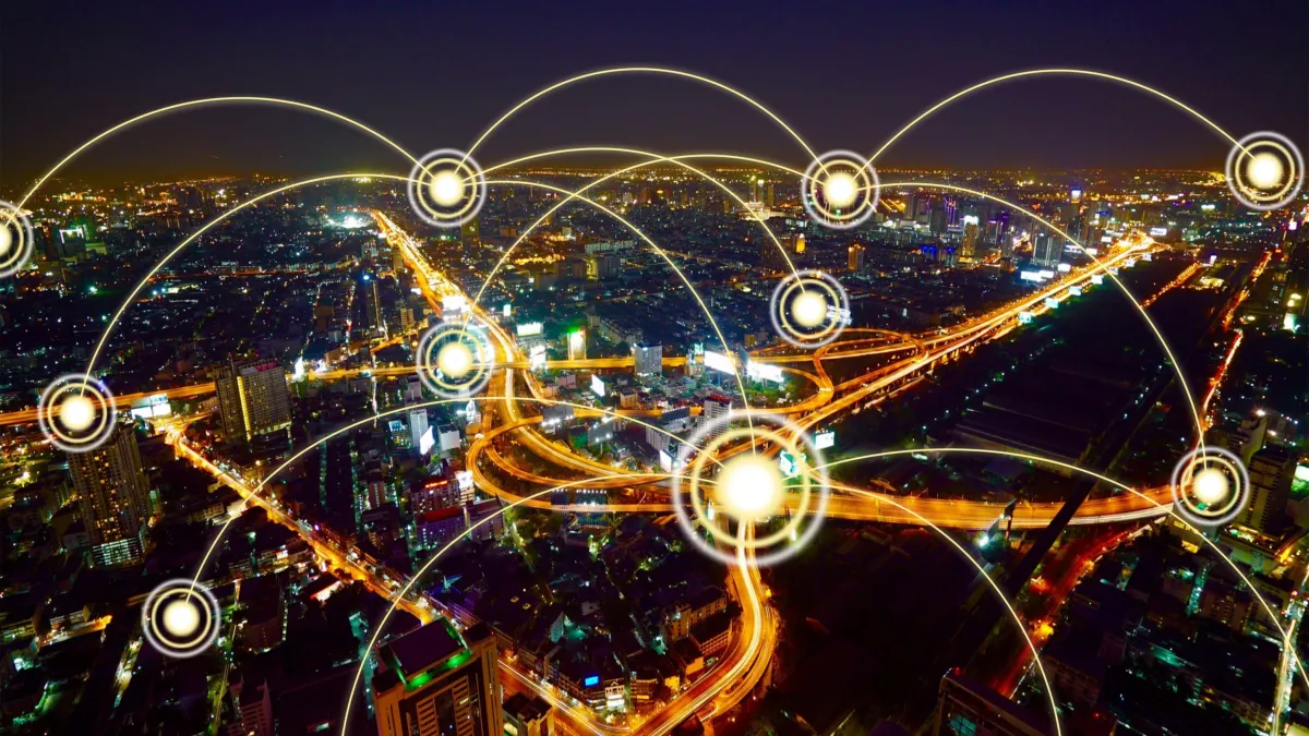 Night aerial view of a city with illuminated roads connected by glowing network nodes.